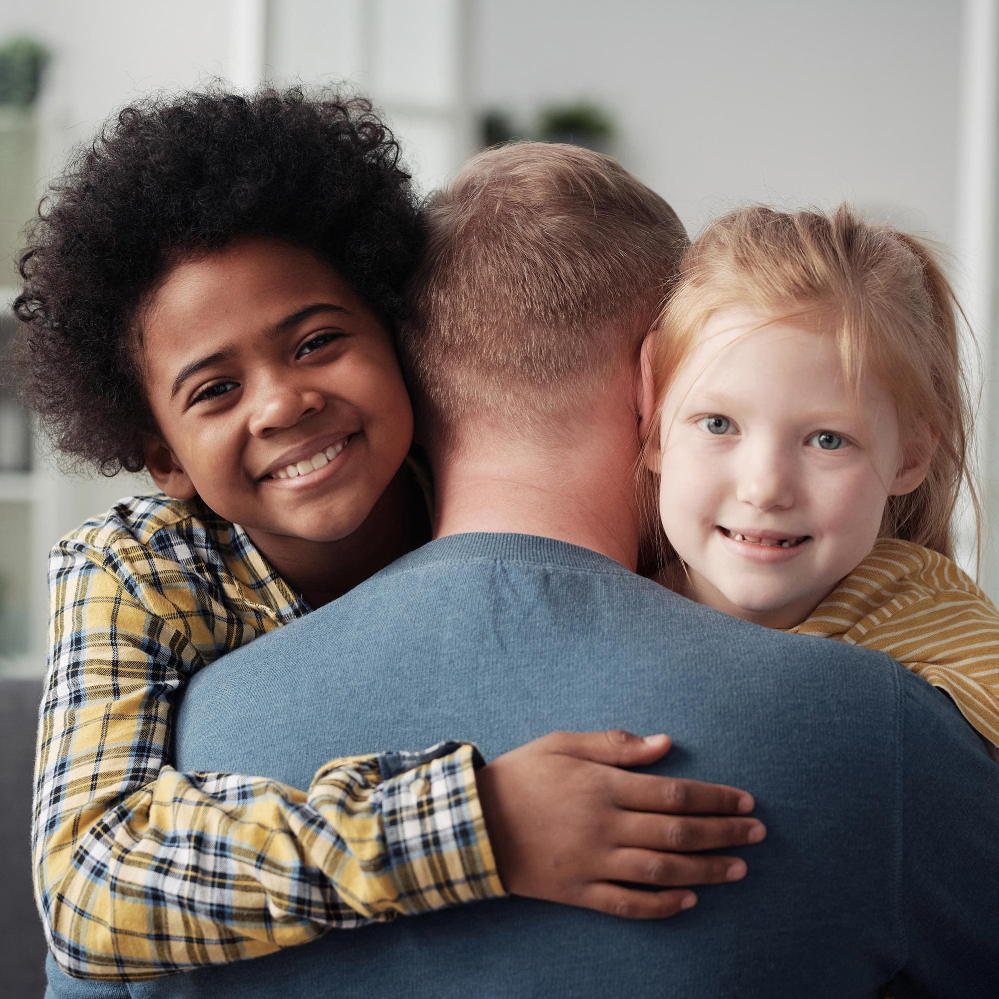 A father hugging his mixed race children.